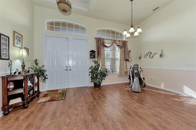 foyer with a notable chandelier, light hardwood / wood-style flooring, and a high ceiling