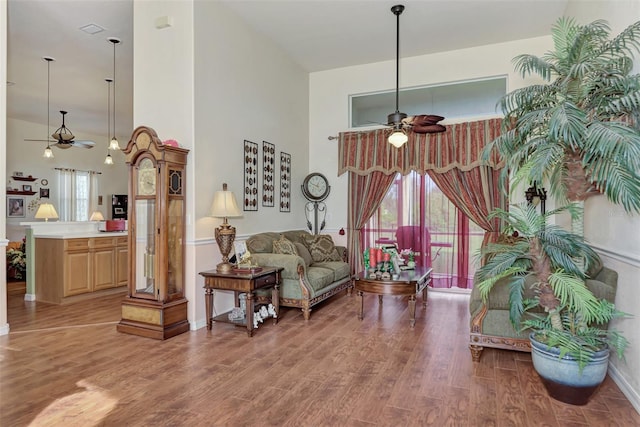 living room with plenty of natural light, a towering ceiling, ceiling fan, and hardwood / wood-style flooring