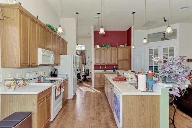 kitchen with light hardwood / wood-style flooring, hanging light fixtures, white appliances, and sink