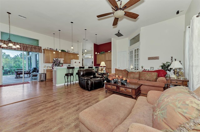 living room featuring light hardwood / wood-style flooring and ceiling fan with notable chandelier