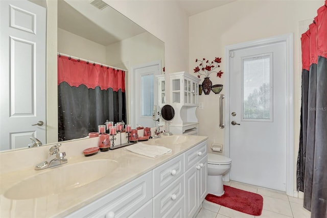 bathroom featuring dual bowl vanity, tile flooring, and toilet