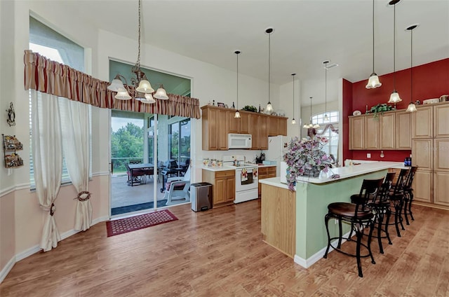 kitchen featuring white appliances, pendant lighting, and light hardwood / wood-style flooring