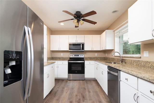 kitchen with ceiling fan, sink, white cabinets, stainless steel appliances, and light wood-type flooring