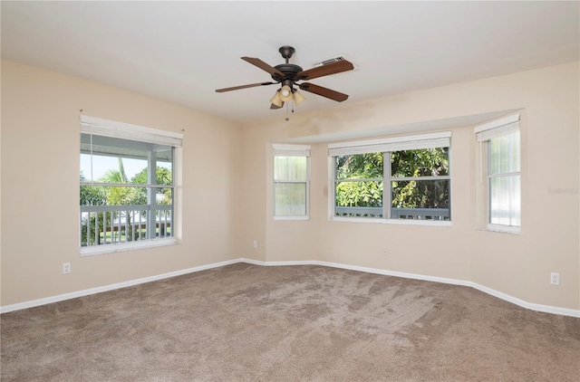 unfurnished room featuring dark colored carpet, ceiling fan, and a healthy amount of sunlight