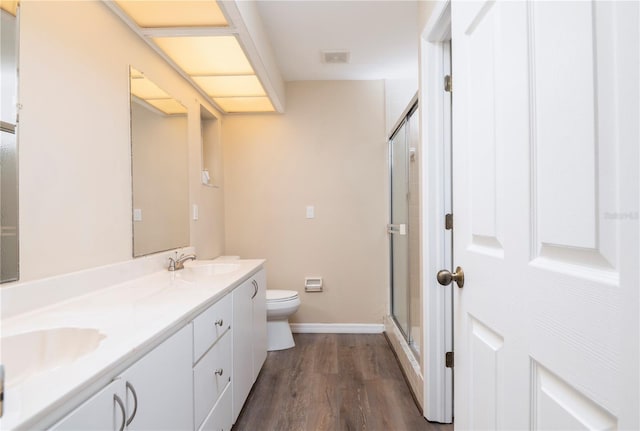 bathroom with double sink, hardwood / wood-style floors, a shower with door, toilet, and oversized vanity