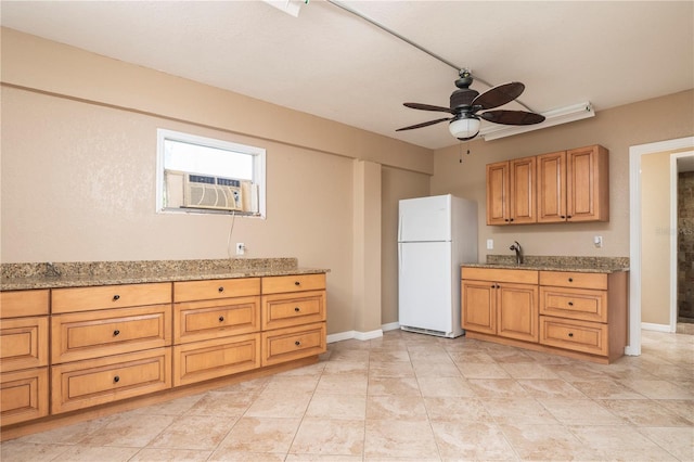 kitchen with light tile floors, white fridge, light stone countertops, ceiling fan, and sink