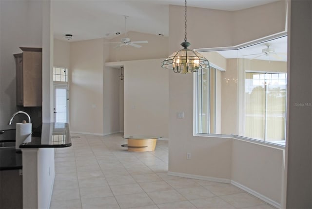 unfurnished dining area with light tile patterned floors, ceiling fan with notable chandelier, and high vaulted ceiling