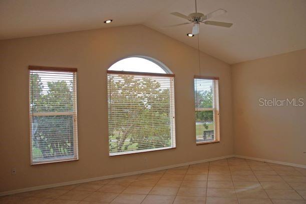 unfurnished room with ceiling fan, lofted ceiling, and light tile patterned flooring