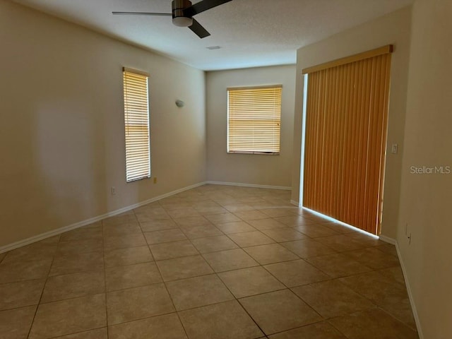 empty room featuring plenty of natural light, ceiling fan, and light tile patterned floors