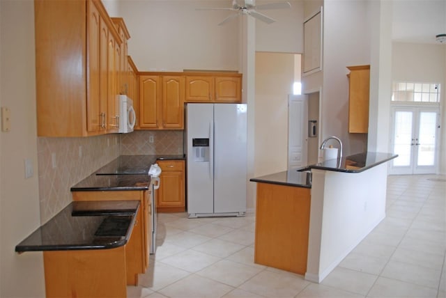 kitchen with kitchen peninsula, light tile patterned floors, white appliances, and tasteful backsplash