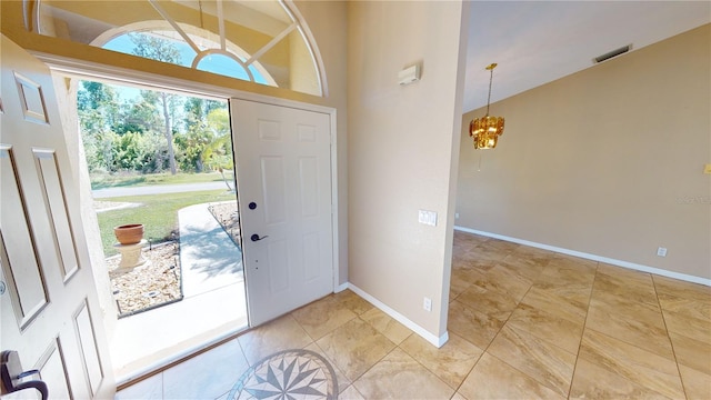 tiled entryway with a high ceiling and a notable chandelier