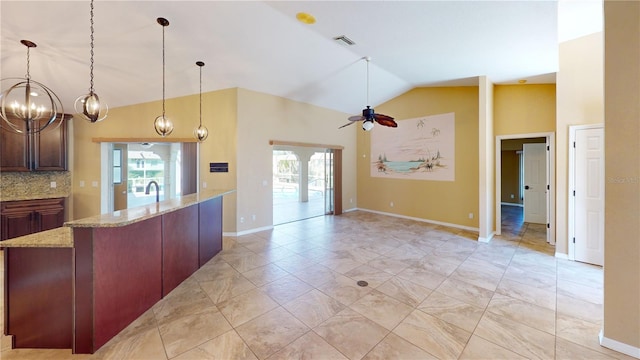 kitchen with light tile floors, decorative light fixtures, light stone countertops, vaulted ceiling, and ceiling fan with notable chandelier