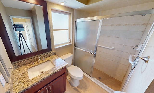 bathroom with toilet, a shower with door, tile floors, and vanity