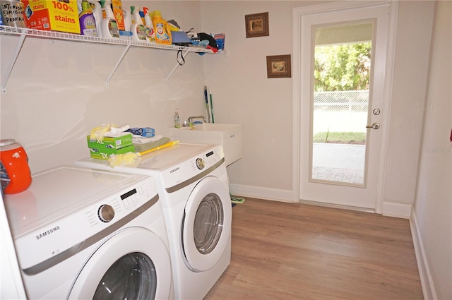 clothes washing area featuring washing machine and clothes dryer, light wood-type flooring, and sink