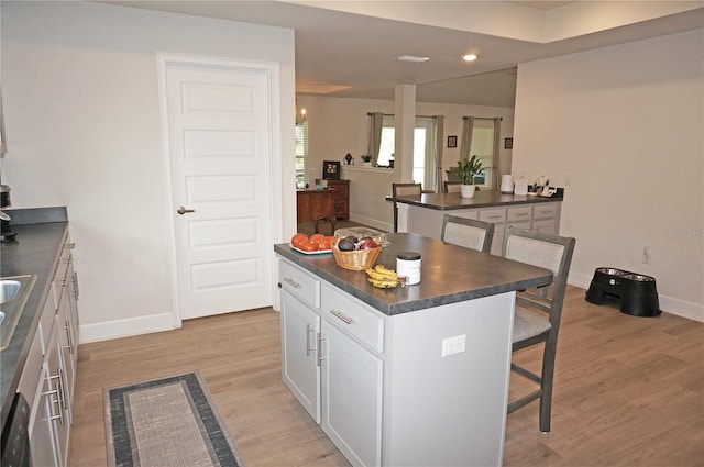 kitchen featuring white cabinets, a breakfast bar, a kitchen island, and light wood-type flooring