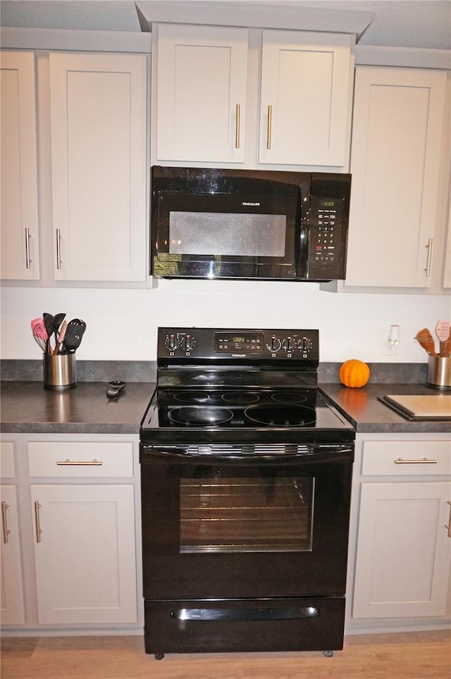 kitchen featuring light wood-type flooring, white cabinets, and black appliances