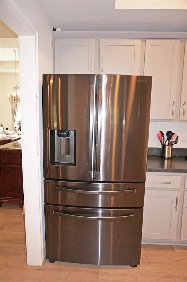 room details featuring stainless steel refrigerator with ice dispenser, a chandelier, and light hardwood / wood-style flooring