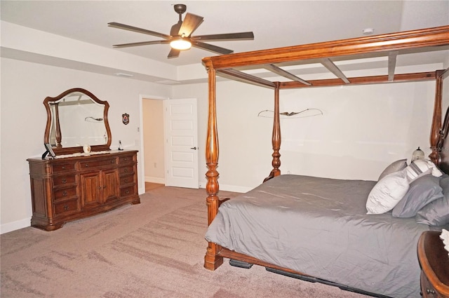 bedroom with light colored carpet, a tray ceiling, and ceiling fan