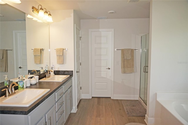 bathroom featuring independent shower and bath, dual sinks, hardwood / wood-style floors, and oversized vanity