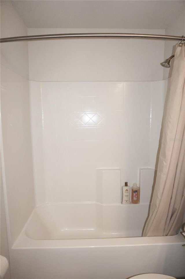 bathroom with shower / bath combination with curtain and toilet