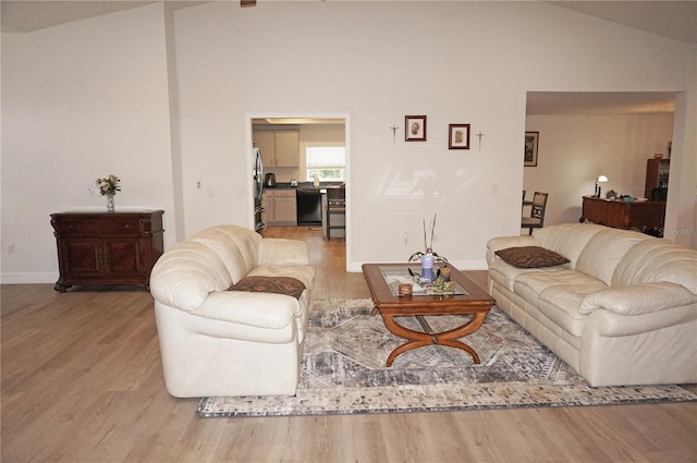 living room featuring high vaulted ceiling and light wood-type flooring