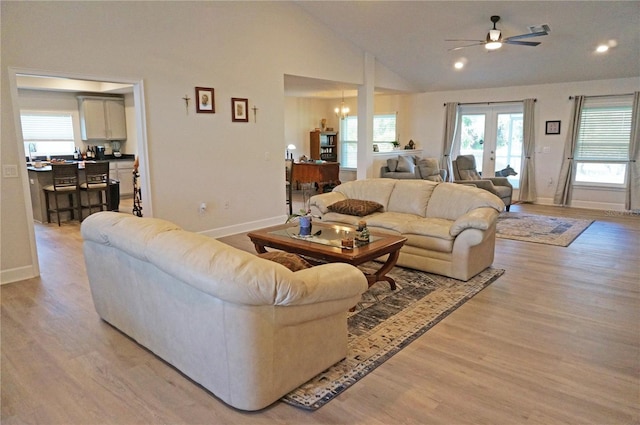 living room with french doors, high vaulted ceiling, light wood-type flooring, and ceiling fan with notable chandelier