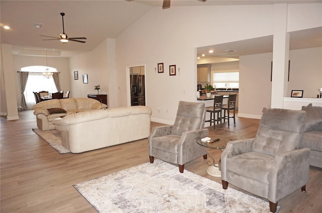 living room featuring high vaulted ceiling, sink, ceiling fan, and light hardwood / wood-style flooring