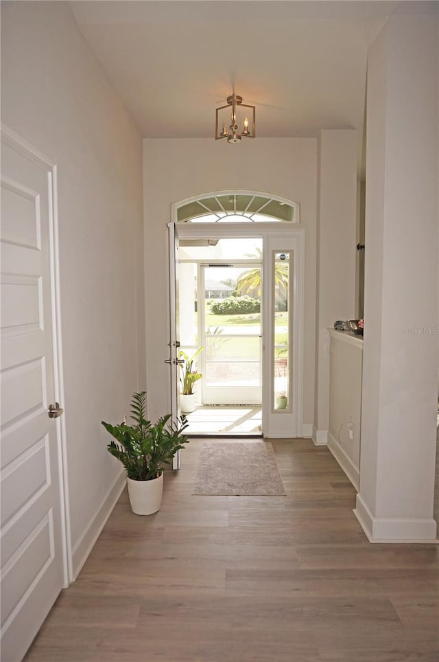 doorway with a chandelier and light wood-type flooring