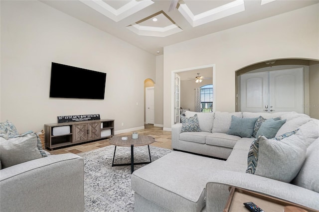 living room with coffered ceiling, ceiling fan, light tile floors, beam ceiling, and french doors