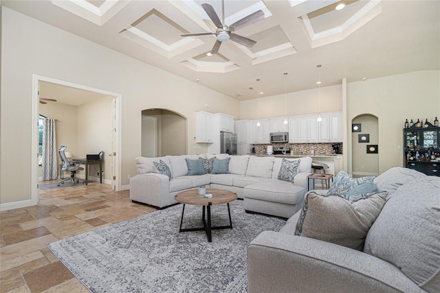 tiled living room with coffered ceiling, ceiling fan, a towering ceiling, and beamed ceiling