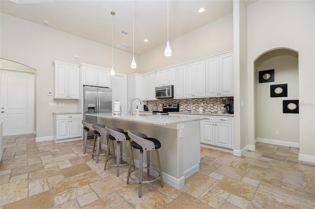 kitchen featuring stainless steel appliances, white cabinets, and a towering ceiling