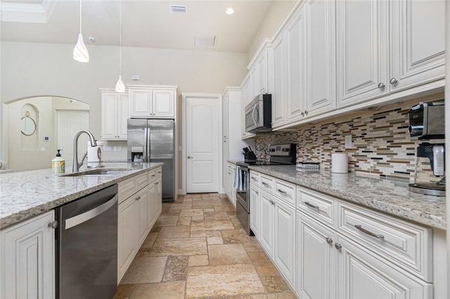 kitchen with tasteful backsplash, white cabinets, appliances with stainless steel finishes, and light stone counters