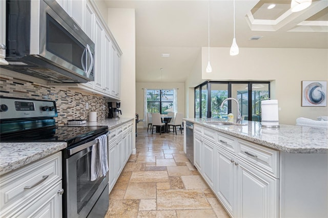 kitchen with pendant lighting, light tile floors, appliances with stainless steel finishes, white cabinetry, and backsplash