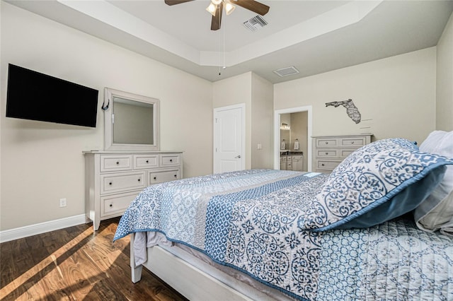 bedroom with a raised ceiling, dark wood-type flooring, ceiling fan, and ensuite bathroom