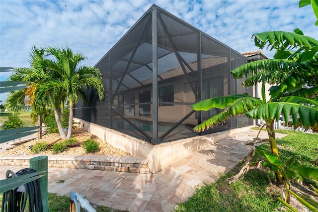 rear view of house with glass enclosure and a patio