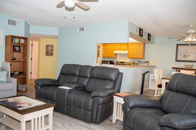 living room featuring a textured ceiling, ceiling fan, and light hardwood / wood-style flooring