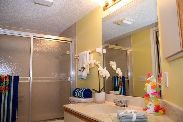 bathroom featuring vanity, an enclosed shower, and a textured ceiling