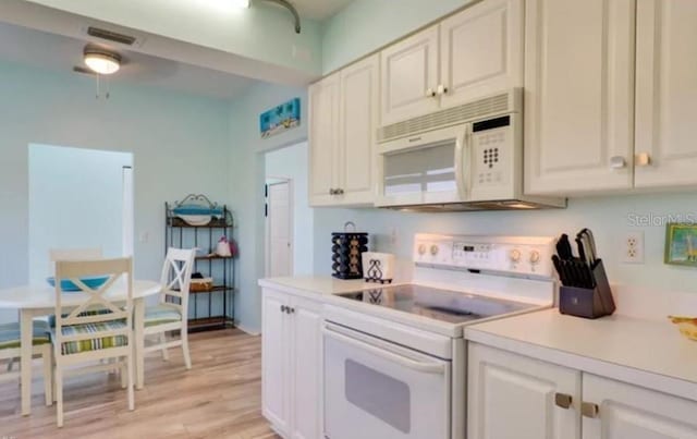 kitchen with white appliances, white cabinets, and light hardwood / wood-style flooring