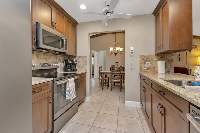 kitchen with light stone countertops, tasteful backsplash, appliances with stainless steel finishes, and ceiling fan with notable chandelier