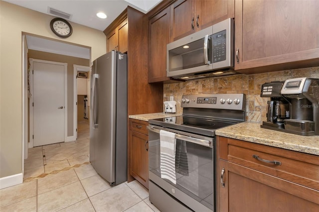 kitchen with light stone countertops, tasteful backsplash, light tile flooring, and stainless steel appliances