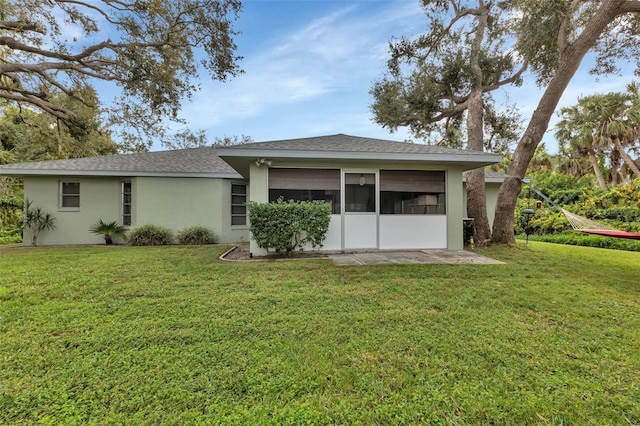 rear view of property featuring a lawn and a sunroom