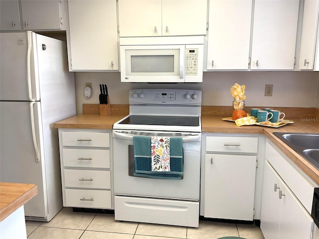 kitchen with light tile patterned floors, white appliances, and white cabinetry