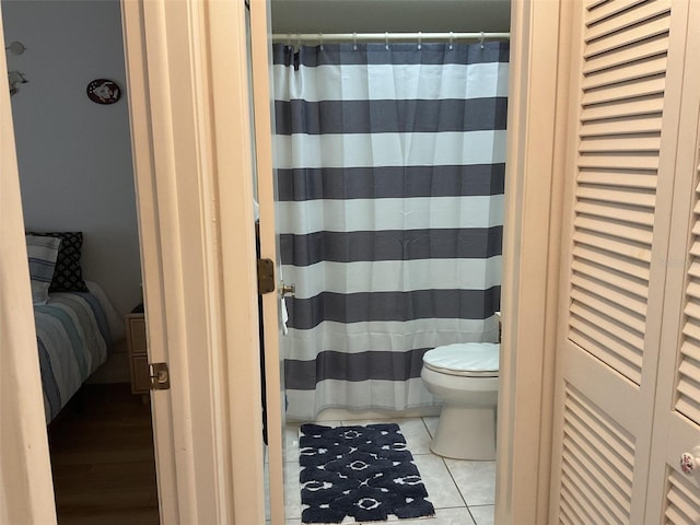 bathroom featuring walk in shower, toilet, and tile patterned floors