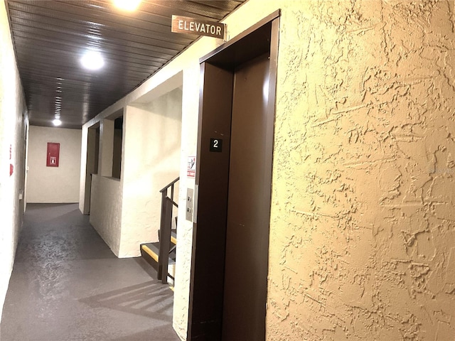 hall with wood ceiling, elevator, and concrete flooring