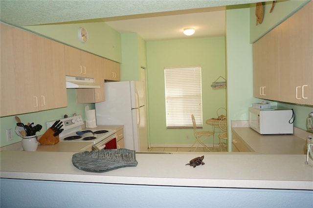 kitchen with white appliances, kitchen peninsula, and light brown cabinetry