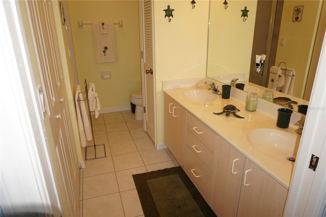 bathroom featuring toilet, double sink, vanity with extensive cabinet space, and tile flooring