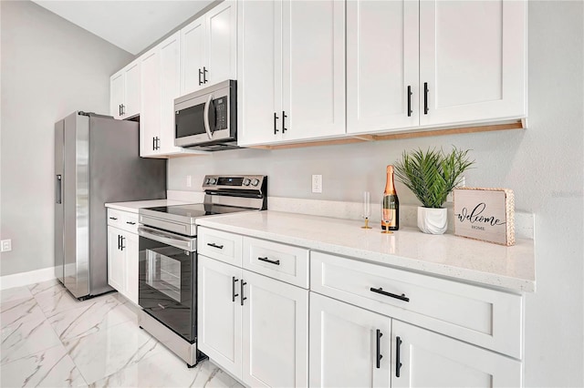 kitchen with stainless steel appliances, white cabinetry, and light stone countertops