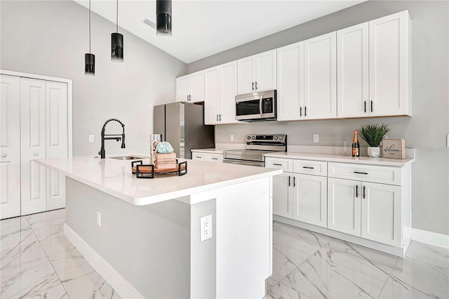 kitchen featuring white cabinetry, stainless steel appliances, sink, hanging light fixtures, and a center island with sink