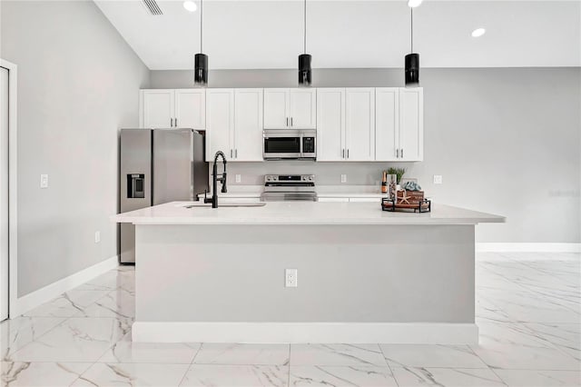 kitchen with appliances with stainless steel finishes, hanging light fixtures, and a kitchen island with sink