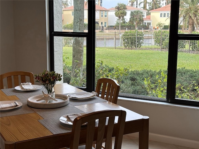 dining area with tile patterned flooring, a water view, and plenty of natural light